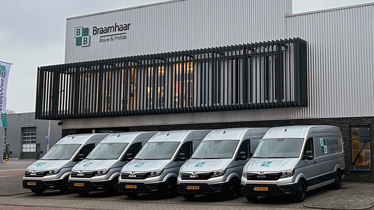 Vooraanzicht van het hoofdkantoor van Bouwbedrijf Braamhaar, groot pand met meerdere bedrijfsbusjes geparkeerd.