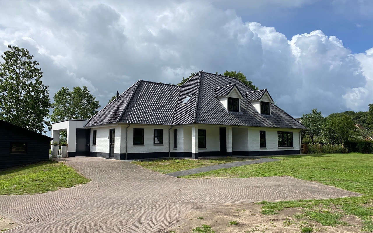 Moderne woning in Gorssel met witte bakstenen en een donkere dak.