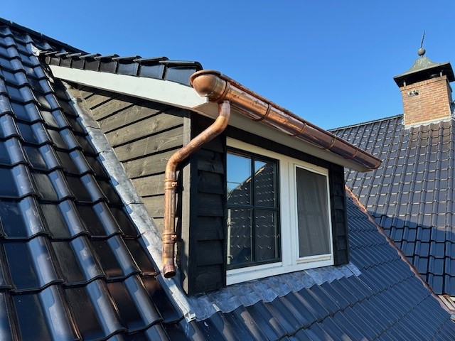 Raam op een dak met donkere dakpannen.