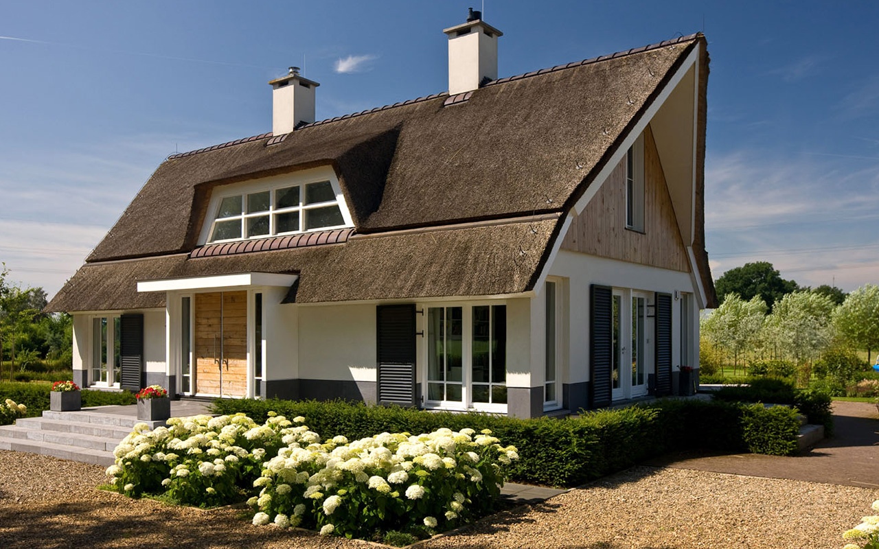 Een witte villa met rieten dak gebouwd door bouwbedrijf braamhaar.