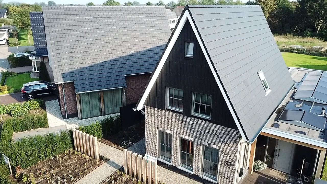Moderne nieuwbouwwoning met karakteristieke puntgevel, steenaccenten en duurzaam dak, gebouwd door Bouwbedrijf Braamhaar in een groene woonomgeving.